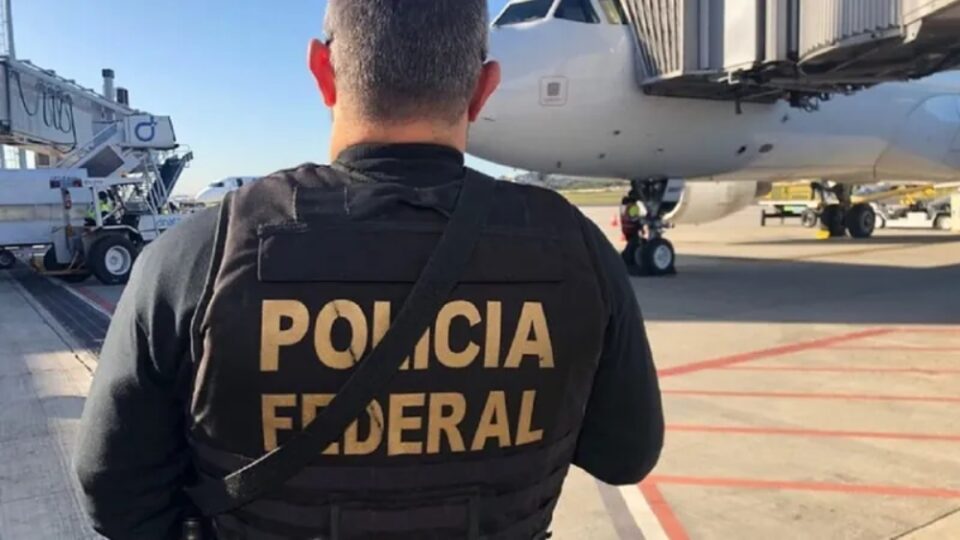 Agente da polícia federal em frente a um avião