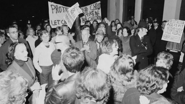 Grupo de manifestantes protestam em Londres durante a primeira reunião aberta do PIE em 1977